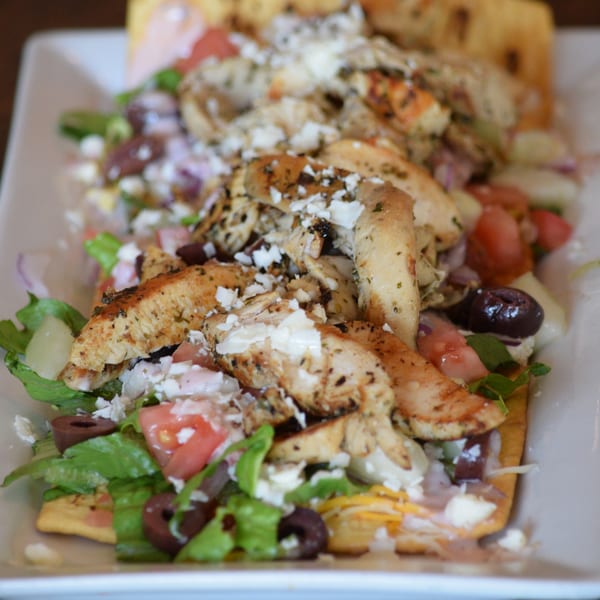 Grilled chicken strips, feta cheese, olives, tomatoes, and lettuce on flatbread.