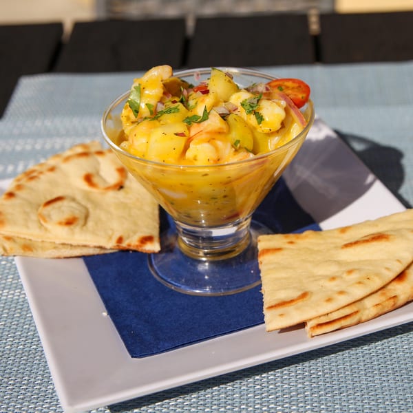 Spiro's Taverna's shrimp ceviche in a glass, garnished with herbs, served with pita bread.