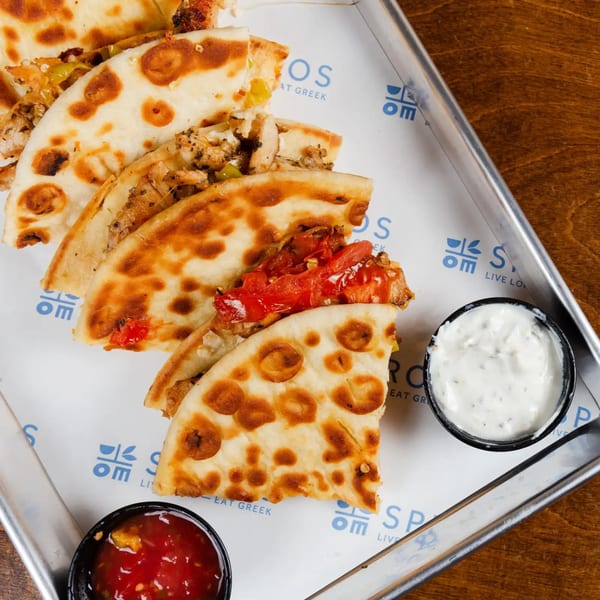 Spiro's Taverna quesadillas with red and white dipping sauces on a branded metal tray.