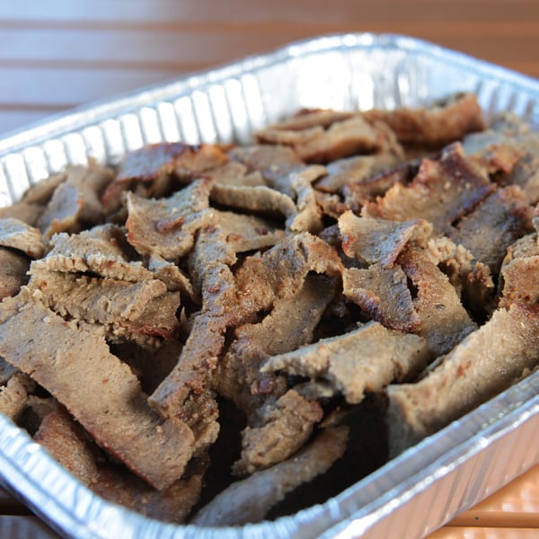 Close-up of gyro meat slices in a silver foil tray, ready to be served.